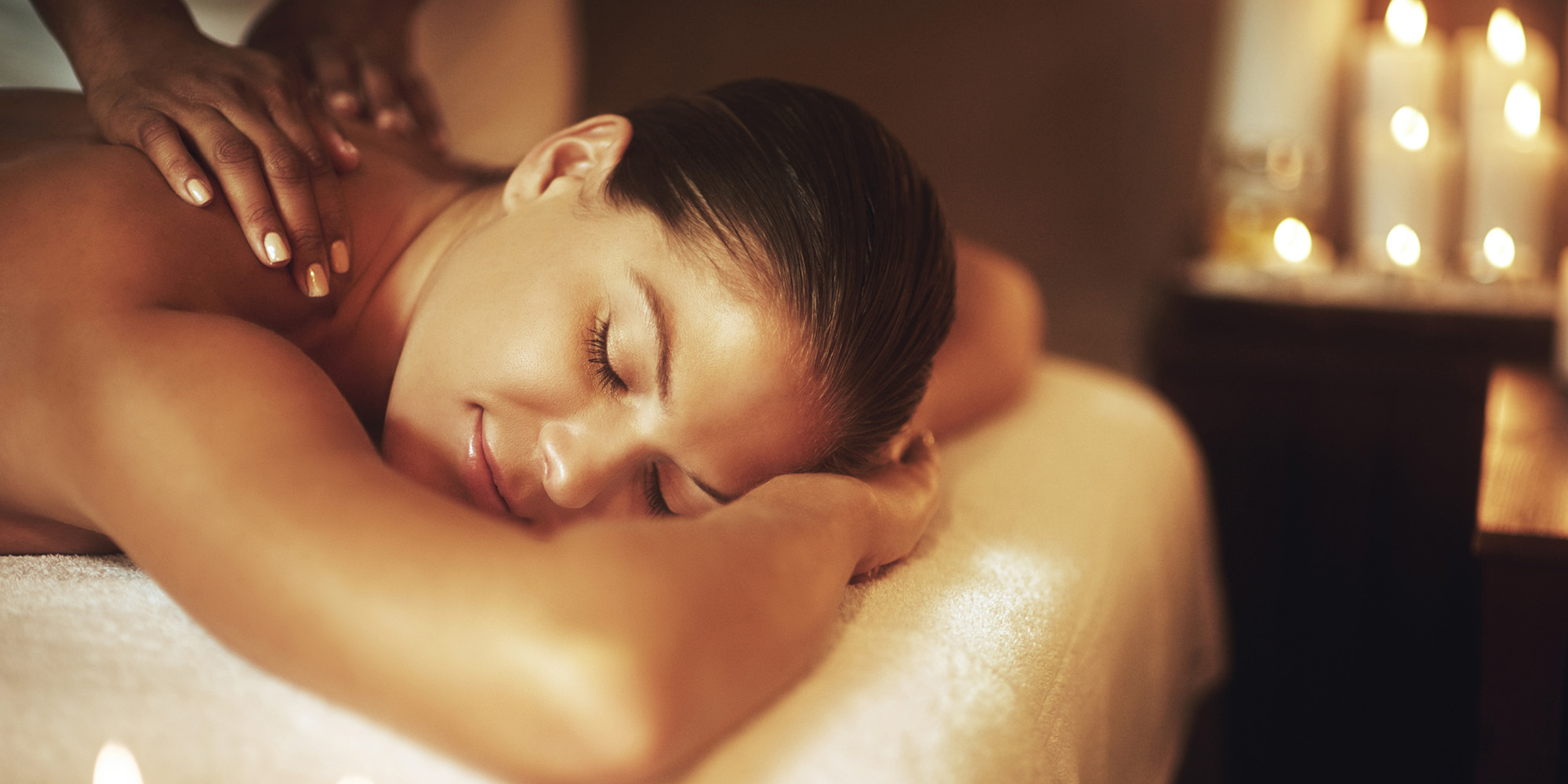 Kvinna som ligger på mage och får en massage i en avslappnande miljö